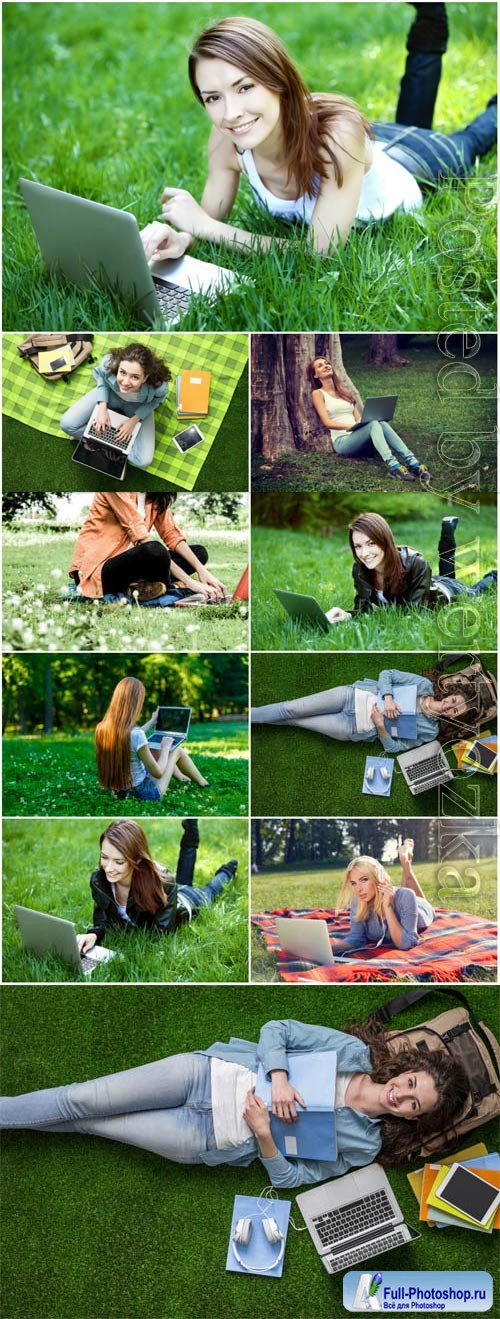 Girls with laptop lie on green grass stock photo